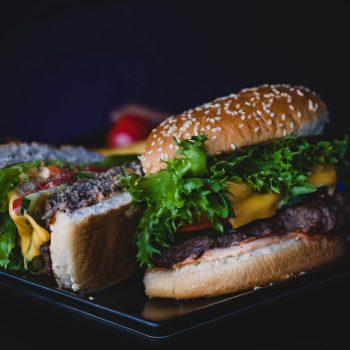 Delicious cheeseburger with lettuce and tomato served on a dark plate.
